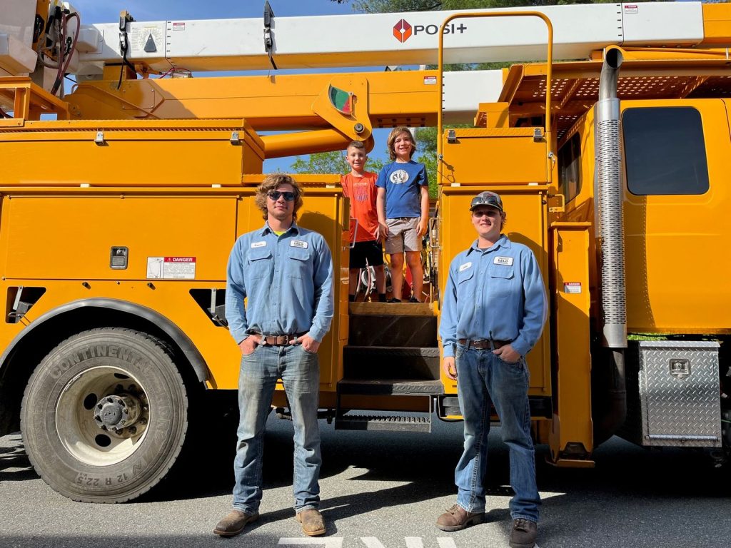 two lineman with two students on a bucket truck